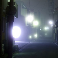 街灯の光がぼんやり広がる霧が出た夜道の写真