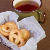 白い皿のクッキーとカップに注がれたお茶のティータイムの写真