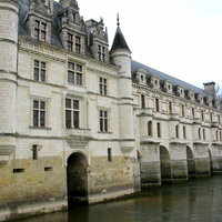 川の上にアーチ型の柱で建つ石造りのシュノンソー城の写真