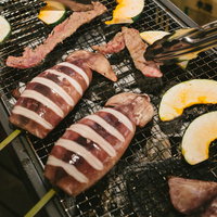 バーベキューで焼く牛肉とイカ焼き、トングで扱う様子の写真