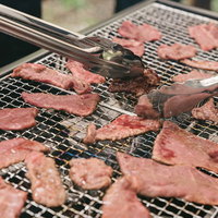 肉だけのBBQを網焼きで調理、トングで返す焼き加減調整の写真