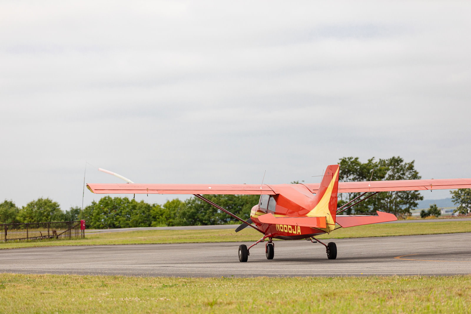 緑に囲まれた滑走路を走る赤と白の小型プロペラ機