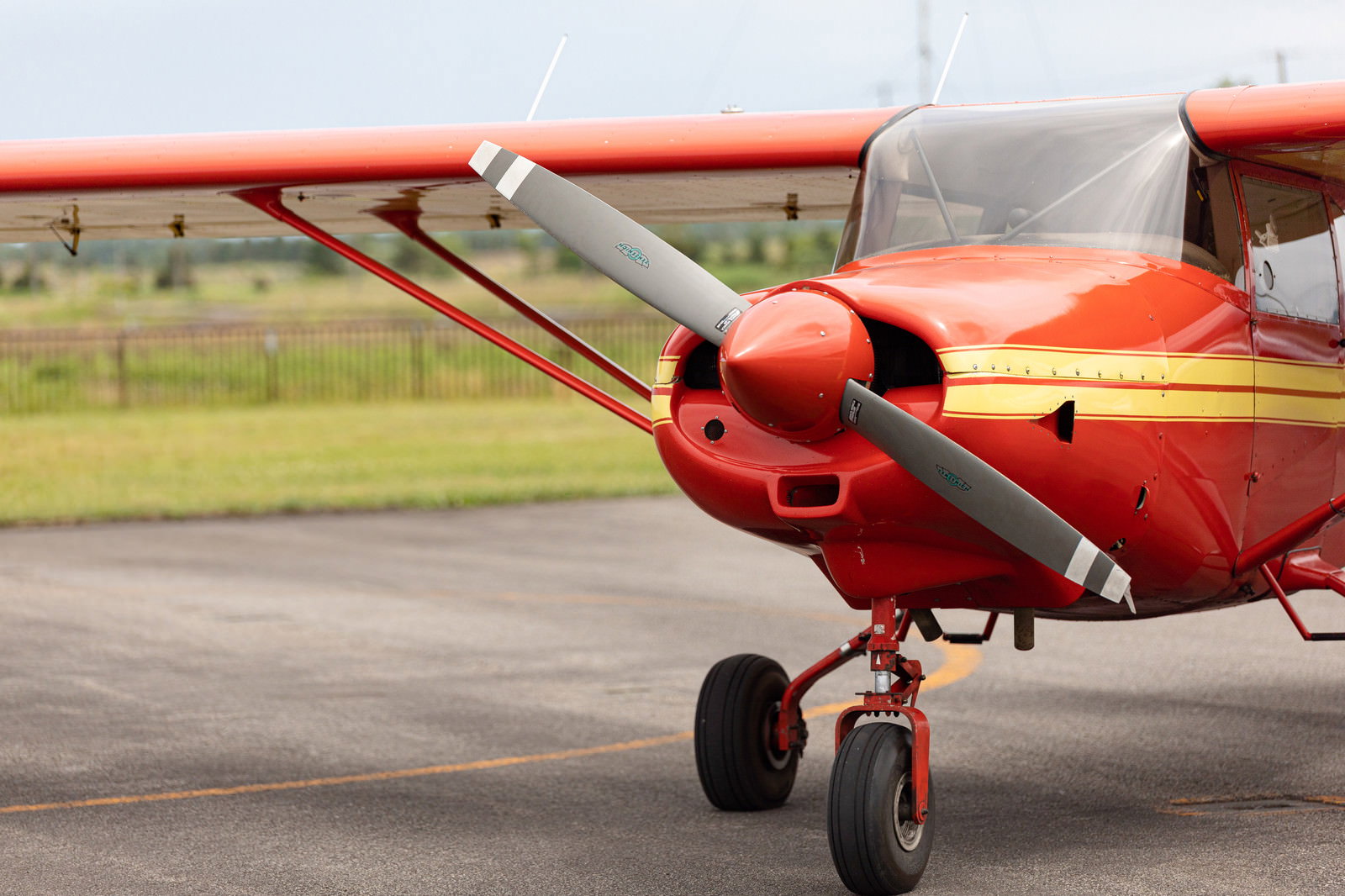 滑走路に駐機している赤と白の小型プロペラ機