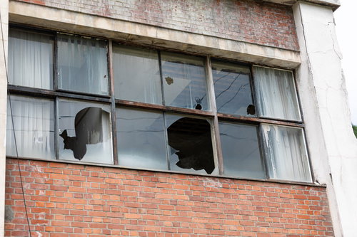 赤茶色のレンガ造りの建物に割れた窓ガラスが残る廃墟