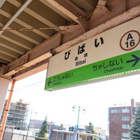 北海道美唄駅のホームに設置された緑色の駅名標の写真