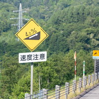 高速道路の傾斜4％標識と速度注意標識、山間部の急勾配区間の写真
