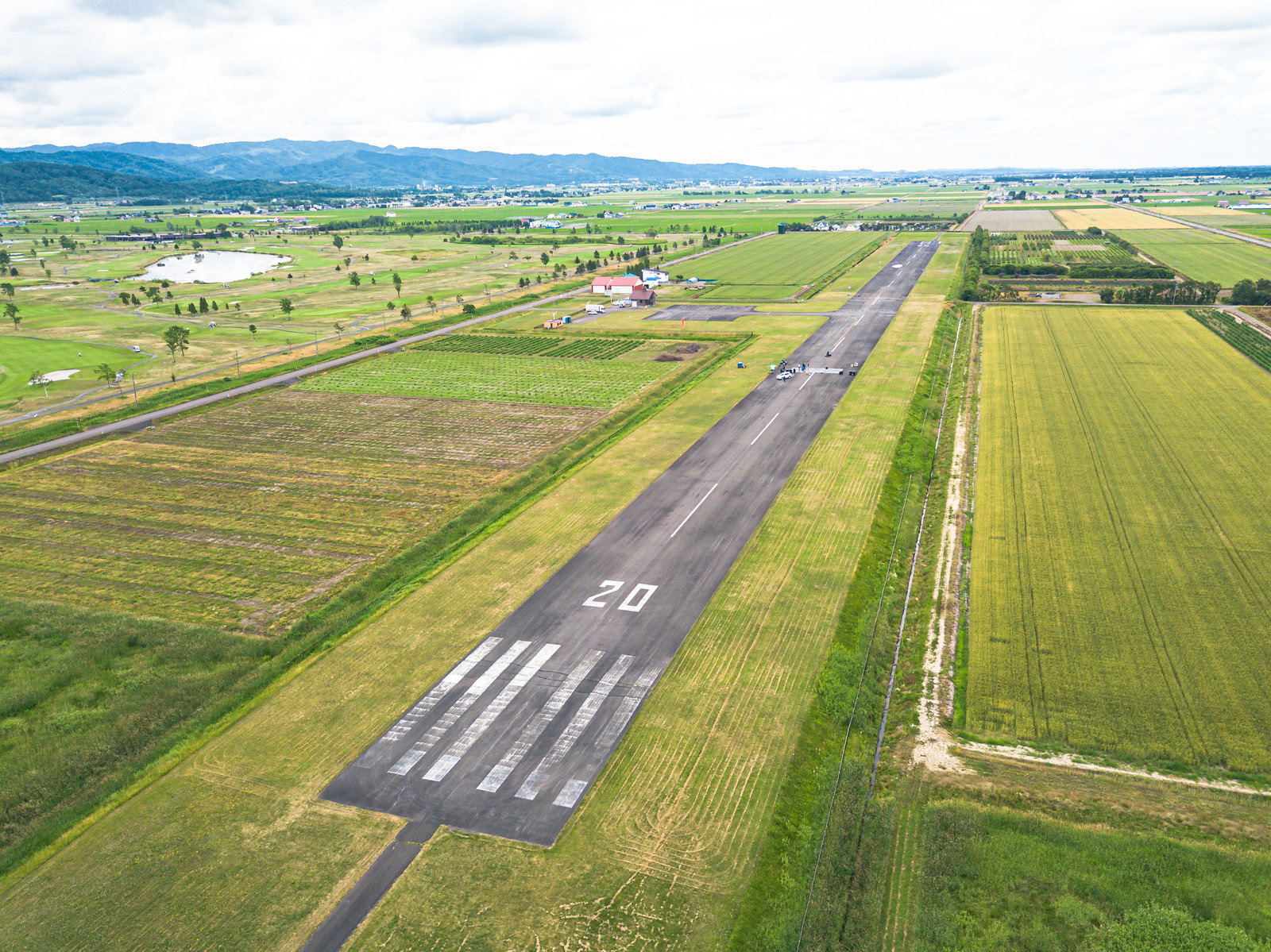 緑の田園風景に囲まれた滑走路を上空から撮影した空撮写真