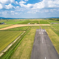 青空の下に広がる滑走路と美唄市の町並み、農地の風景の写真