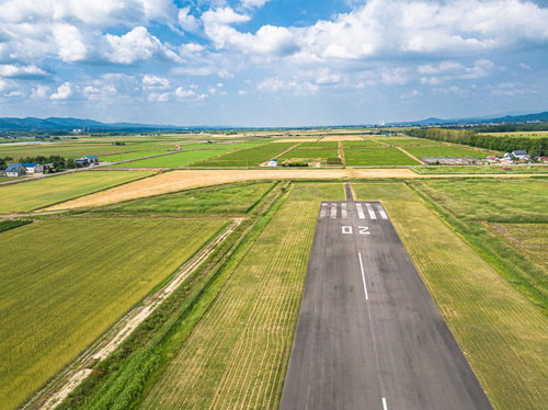 青空の下に広がる滑走路と美唄市の町並み、農地の風景
