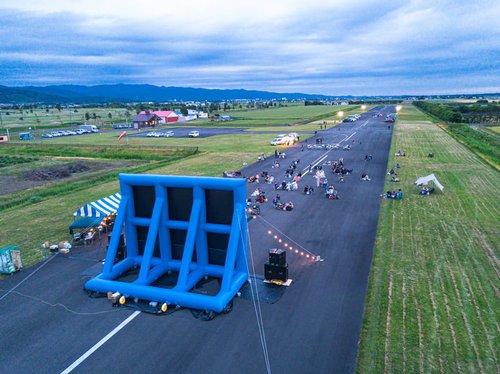 美唄市の飛行場滑走路で開催される野外映画の上映会に集まる観客