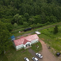 森に囲まれた美唄東明駅の赤い駅舎と廃線跡を上空から撮影の写真