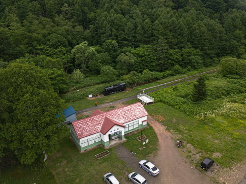 森に囲まれた美唄東明駅の赤い駅舎と廃線跡を上空から撮影