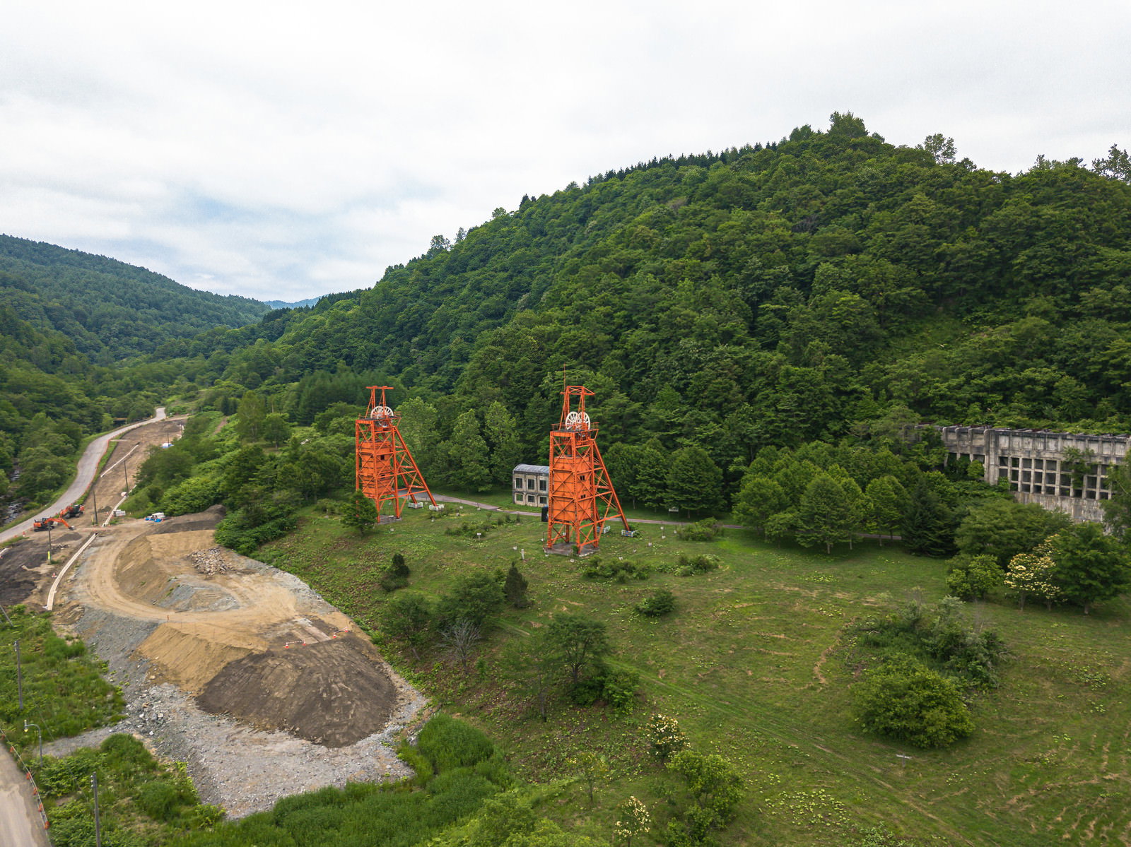 森に囲まれた美唄炭鉱の赤い立坑櫓と原炭ポケットの空撮風景