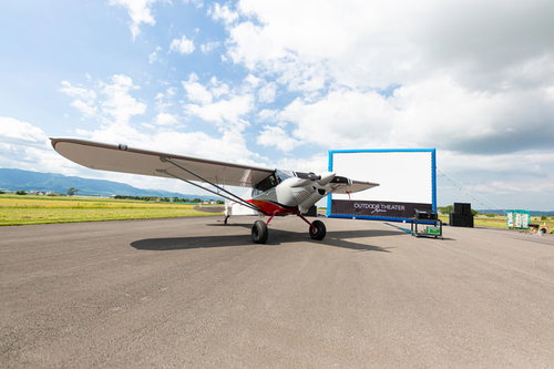 野外シネマと滑走路に駐機する小型プロペラ機