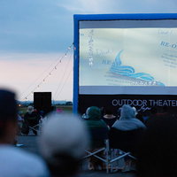 夜間の野外シネマで映画を鑑賞する観客たちの写真