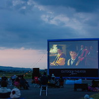 夕暮れの野外シネマでレジャーシートに座り映画を鑑賞する観客たちの写真