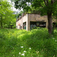 草木が生い茂る閉鎖中の我路郵便局の廃墟の外観の写真