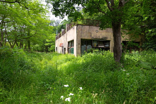 草木が生い茂る閉鎖中の我路郵便局の廃墟の外観