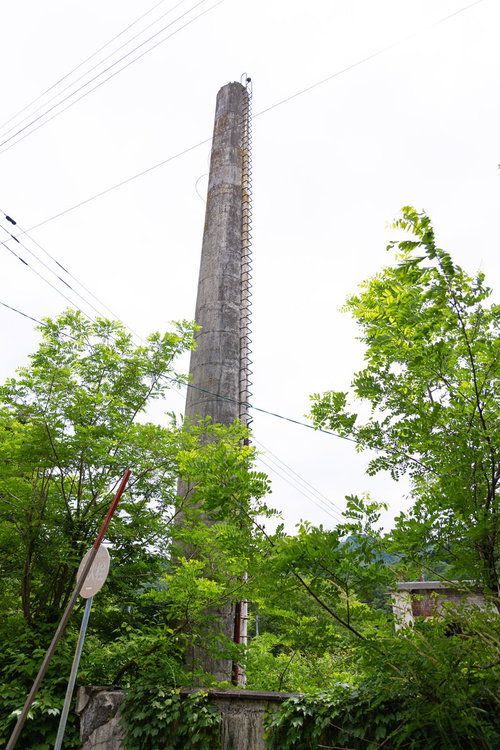新緑に囲まれた焼却炉の高い煙突（我路郵便局）
