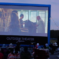 夕暮れ時のアウトドアシアター上映中、大勢の観客が野外映画を鑑賞の写真