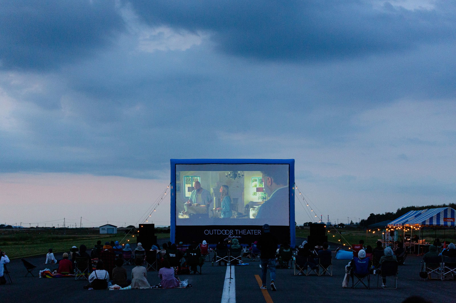 滑走路に設置された大型スクリーンで映画を観賞する観客たち
