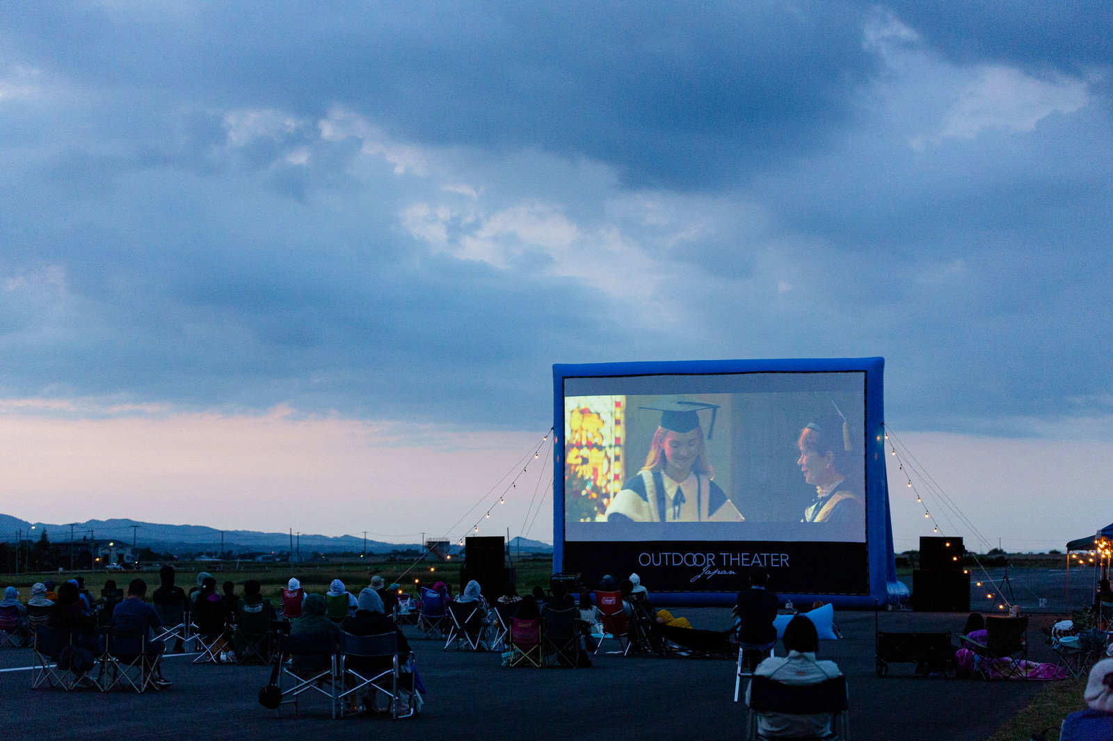 滑走路に設置された大型スクリーンで映画を鑑賞する観客たち