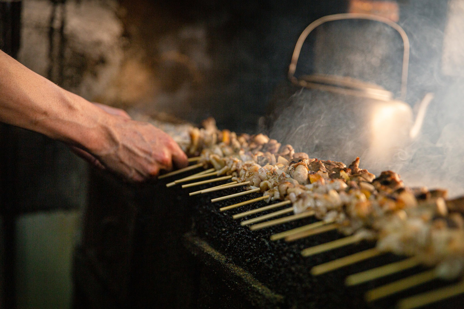 炭火のグリルで美唄焼き鳥を焼く職人の手