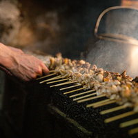 炭火で鳥串を焼く職人の手、美唄焼き鳥の調理風景の写真