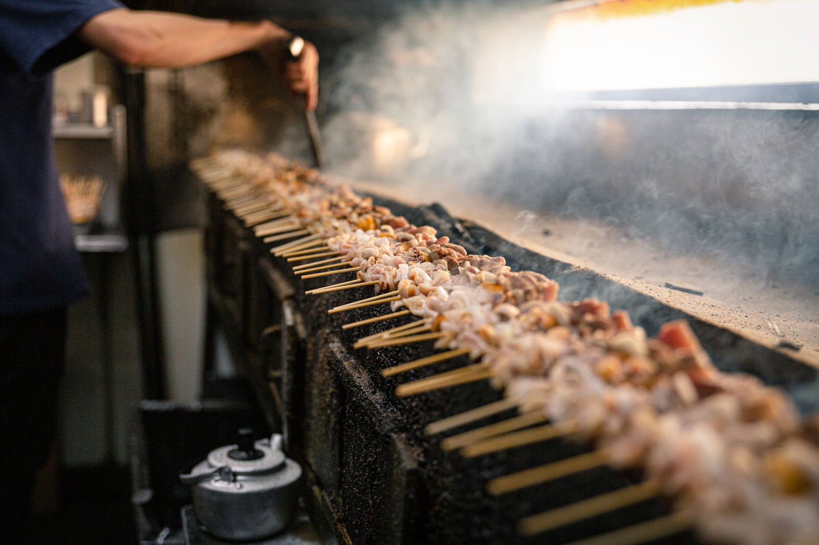 炭火の上で焼かれている美唄焼き鳥と立ち上る白い煙