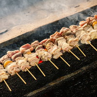 炭火で焼かれる本場の美唄焼き鳥、香ばしい煙が立ち上るの写真