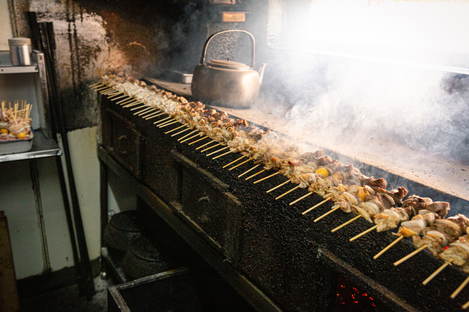 炭火台で焼かれる美唄焼き鳥の串が煙とともに並んでいる様子