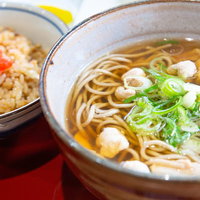 美唄の鶏そばと鶏めし定食、薄切り鶏肉とネギの温かい一品の写真