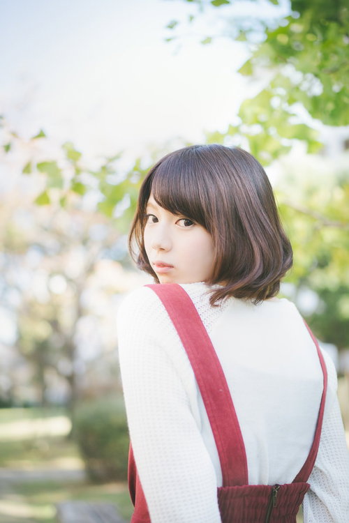 緑に囲まれた公園で振り返る美少女のポートレート