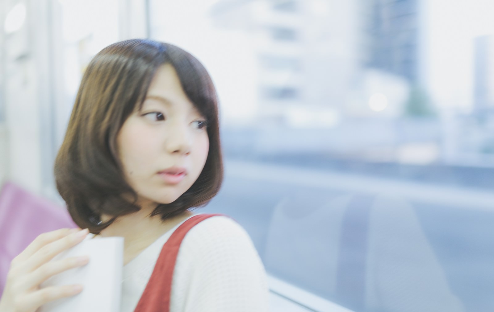 電車で乗り過ごした女性が車窓を見つめている写真［モデル：みき。］