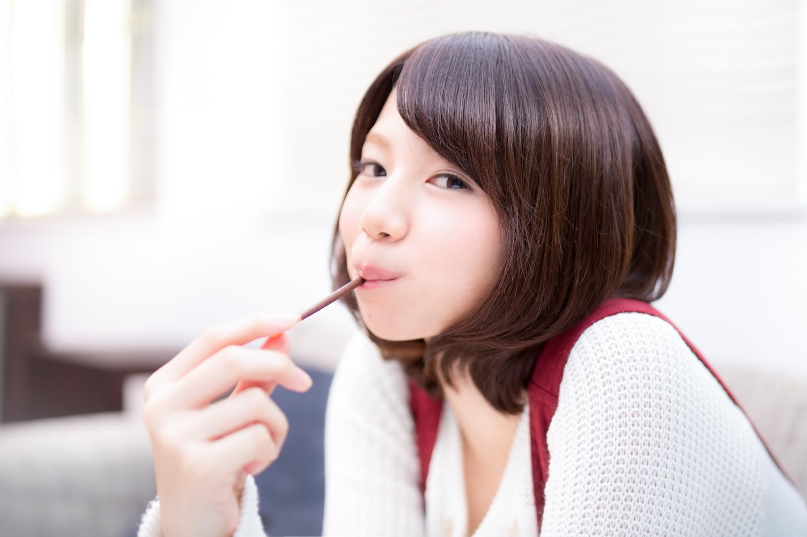 ポッキーを食べる茶色いボブヘアの女性の横顔［モデル：みき。］