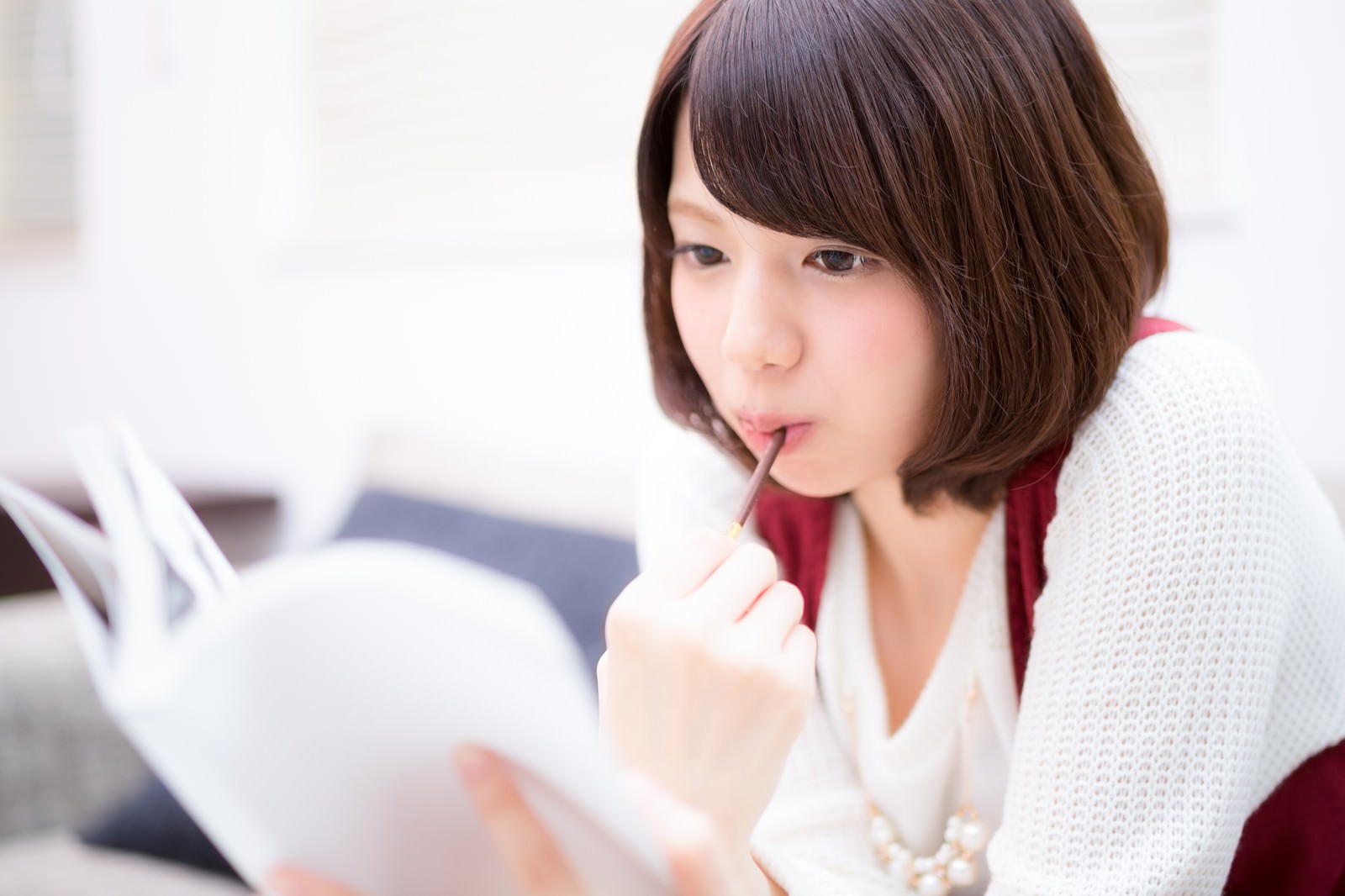 マンガを読みながらポッキーを食べる女性［モデル：みき。］