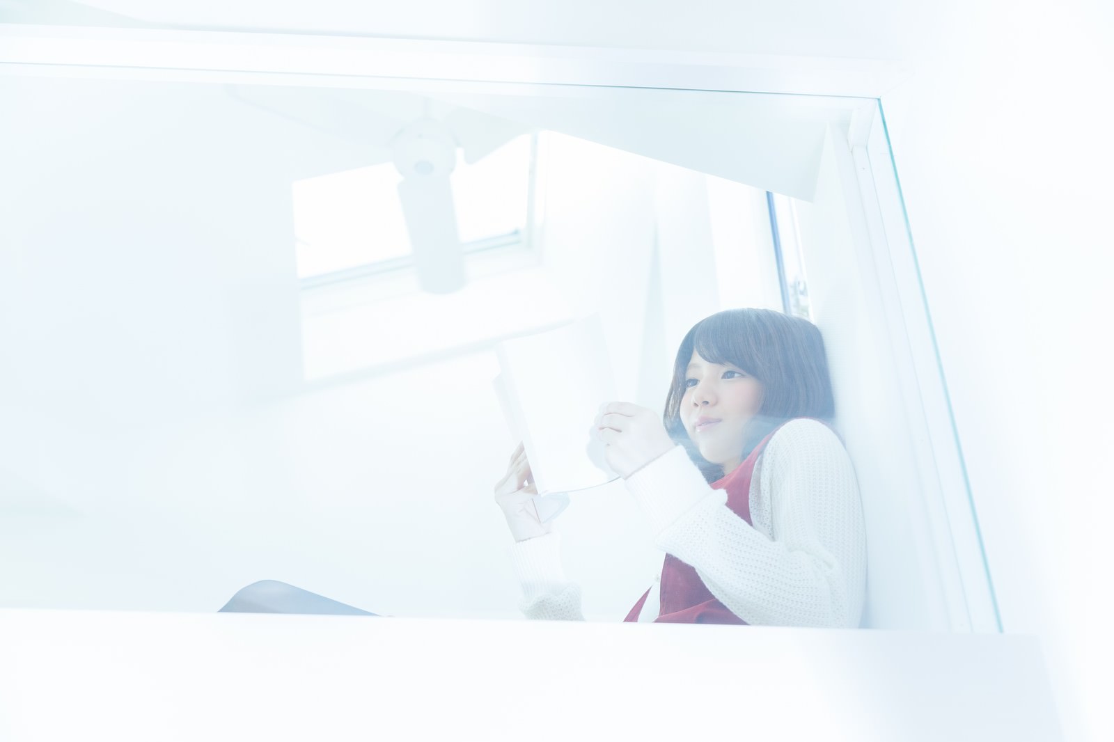 ロフトの窓辺で資料を読む女性［モデル：みき。］