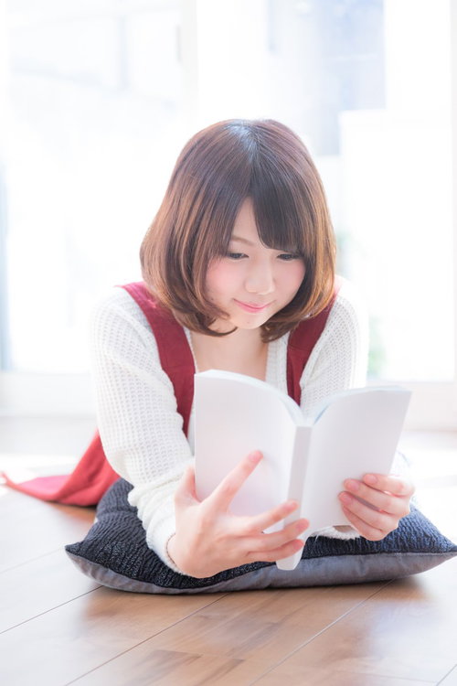 床に座って時間を忘れて夢中でマンガを読む美少女