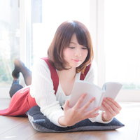 予想のつかない展開にワクワクしながら漫画を読む女性の写真