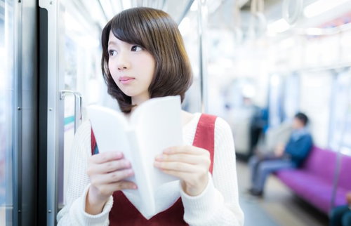 電車の中でマンガを読む美少女、ベージュベストと白いニット帽姿