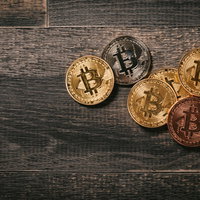 木目の板に置かれたビットコインのメダルの写真