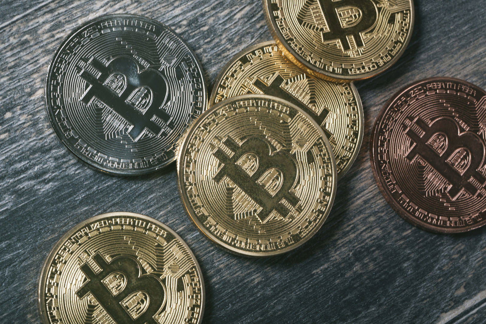 金色と銅色のビットコインマークが刻印されたコインが複数枚重なっている