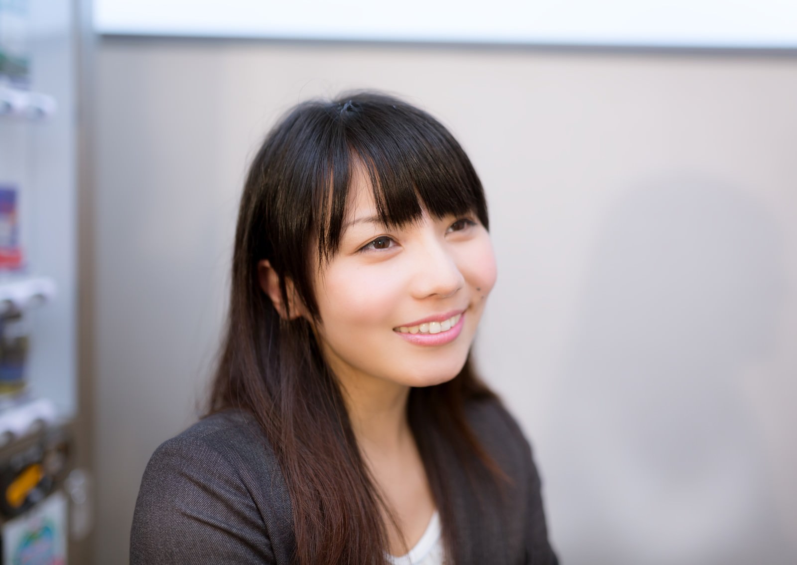 黒いスーツを着た前髪パッツンの女性が上向き視線でにやりと笑う［モデル：Lala］