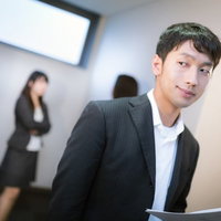 女性社員の会話に耳を傾ける男性社員、オフィスの一角での情報収集シーンの写真