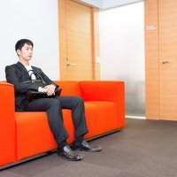 大事な打ち合わせの前に待合室で緊張する新人営業マンの写真
