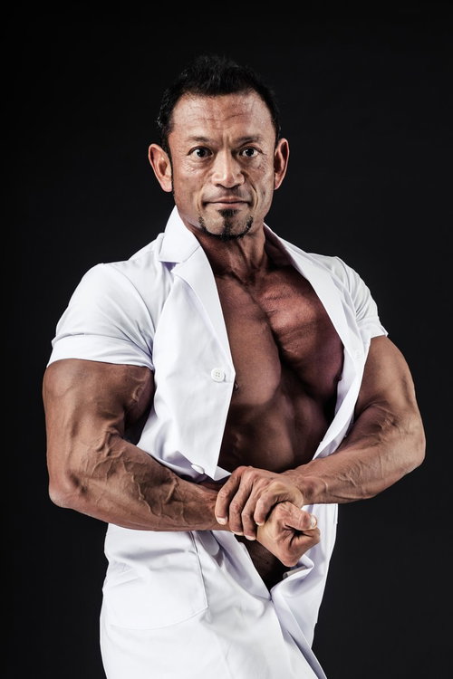 白衣のままサイドチェストポージングを披露する男性ボディビルダー