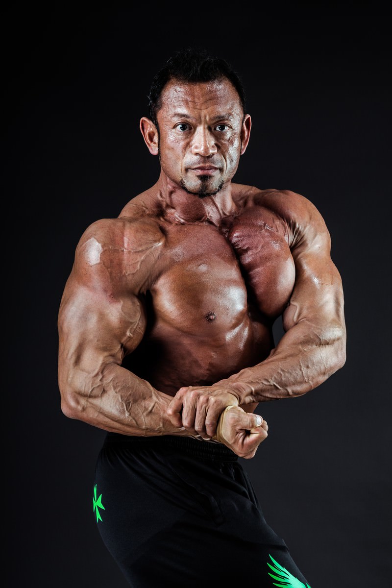 サイドチェストを決めて筋肉を見せるボディビルダーの男性［モデル：パルンボ井若］