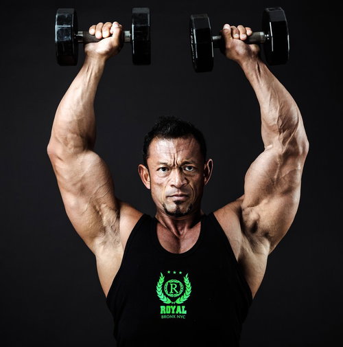 ダンベルを頭上に掲げるボディビルダーのトレーニング