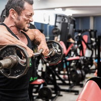 バーベルで大胸筋に負荷をかけるボディビルダーの写真