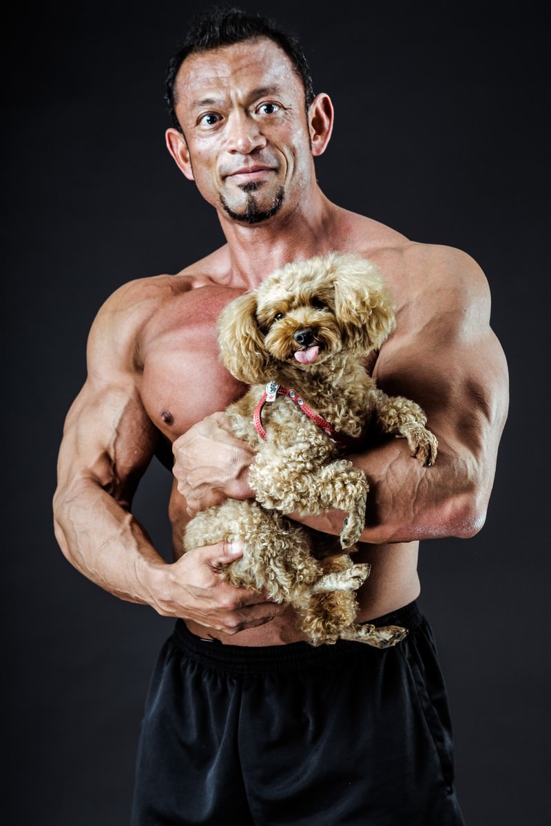 子犬を抱いて上半身をむき出しにしたボディビルダー男性のスタジオポートレート［モデル：パルンボ井若］